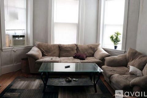 A living room with a glass coffee table and a large sectional sofa.