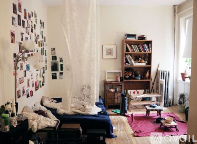 A bedroom with a bed, a bookshelf, and a window with curtains.