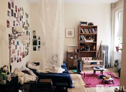 A bedroom with a bed, a bookshelf, and a window with curtains.