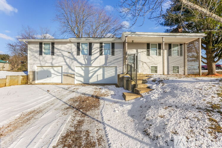 A house with a white garage door and a driveway covered in snow.