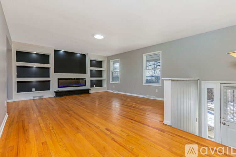 A spacious living room with hardwood floors and built-in entertainment units.
