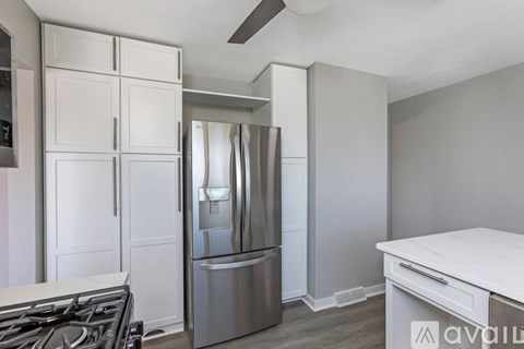 A modern kitchen with a stainless steel refrigerator and a white countertop.