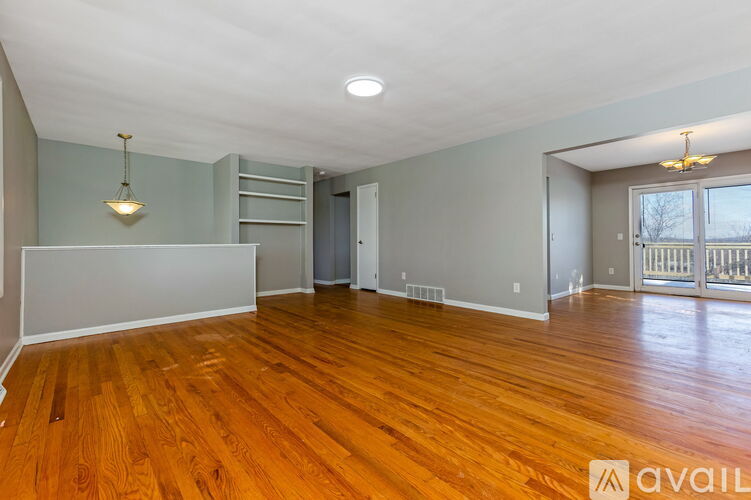 A spacious room with wooden flooring and a large window.