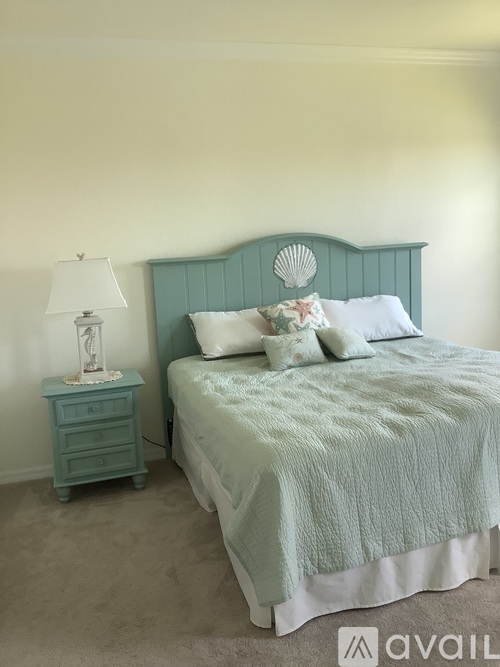 A bed with a blue headboard and a white blanket.