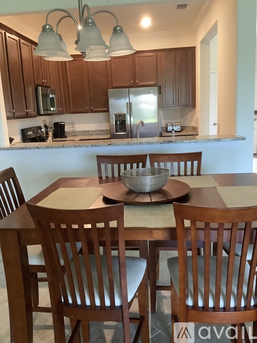 A kitchen with a table and chairs in front of it.