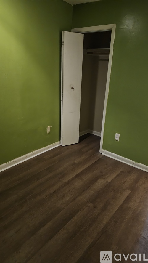 A room with a white door and wooden flooring.