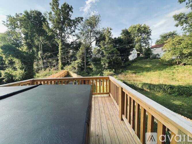 A wooden deck with a black mattress on it surrounded by trees.