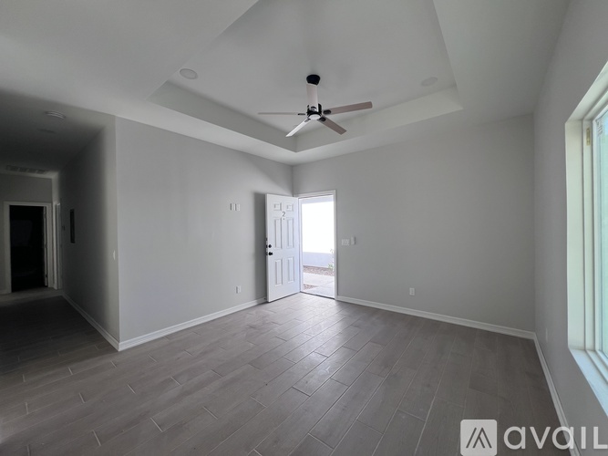 A spacious room with a ceiling fan and a door leading to a hallway.