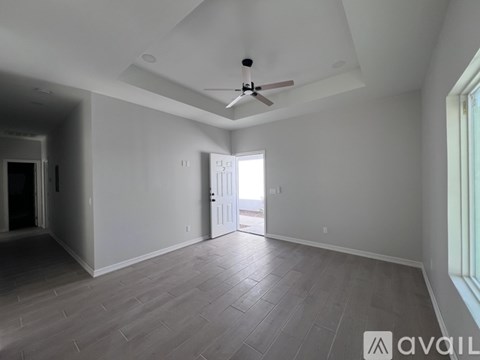 A spacious room with a ceiling fan and a door leading to a hallway.