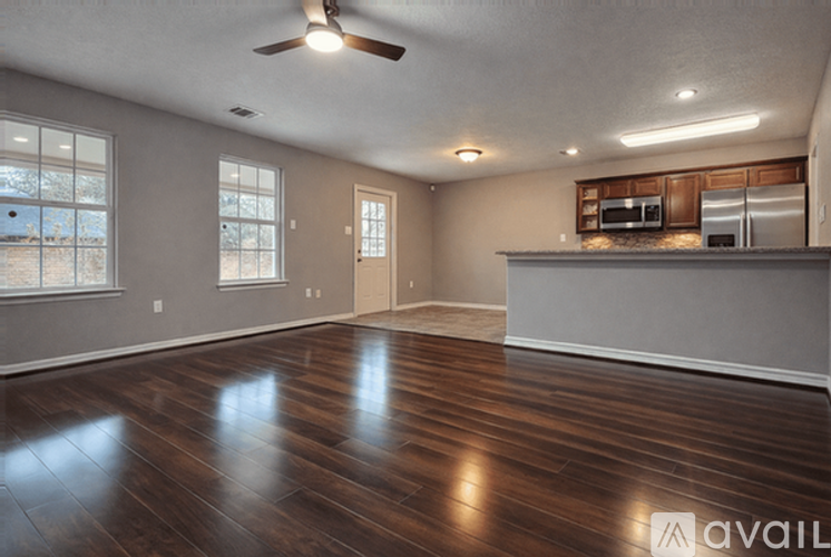 A spacious room with wooden floors and a ceiling fan.