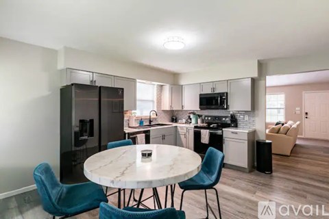 A modern kitchen with a white table and blue chairs.