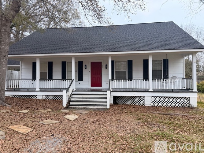 A white house with a red door and black shutters.
