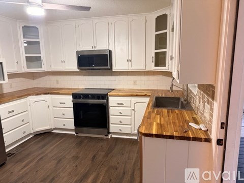 A kitchen with white cabinets and a wooden counter top.