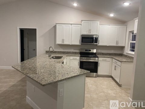 A kitchen with granite countertops and white cabinets.