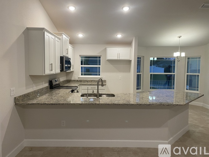 A kitchen with granite countertops and white cabinets.