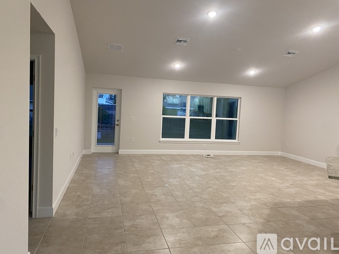 A spacious room with tiled flooring and a large window.