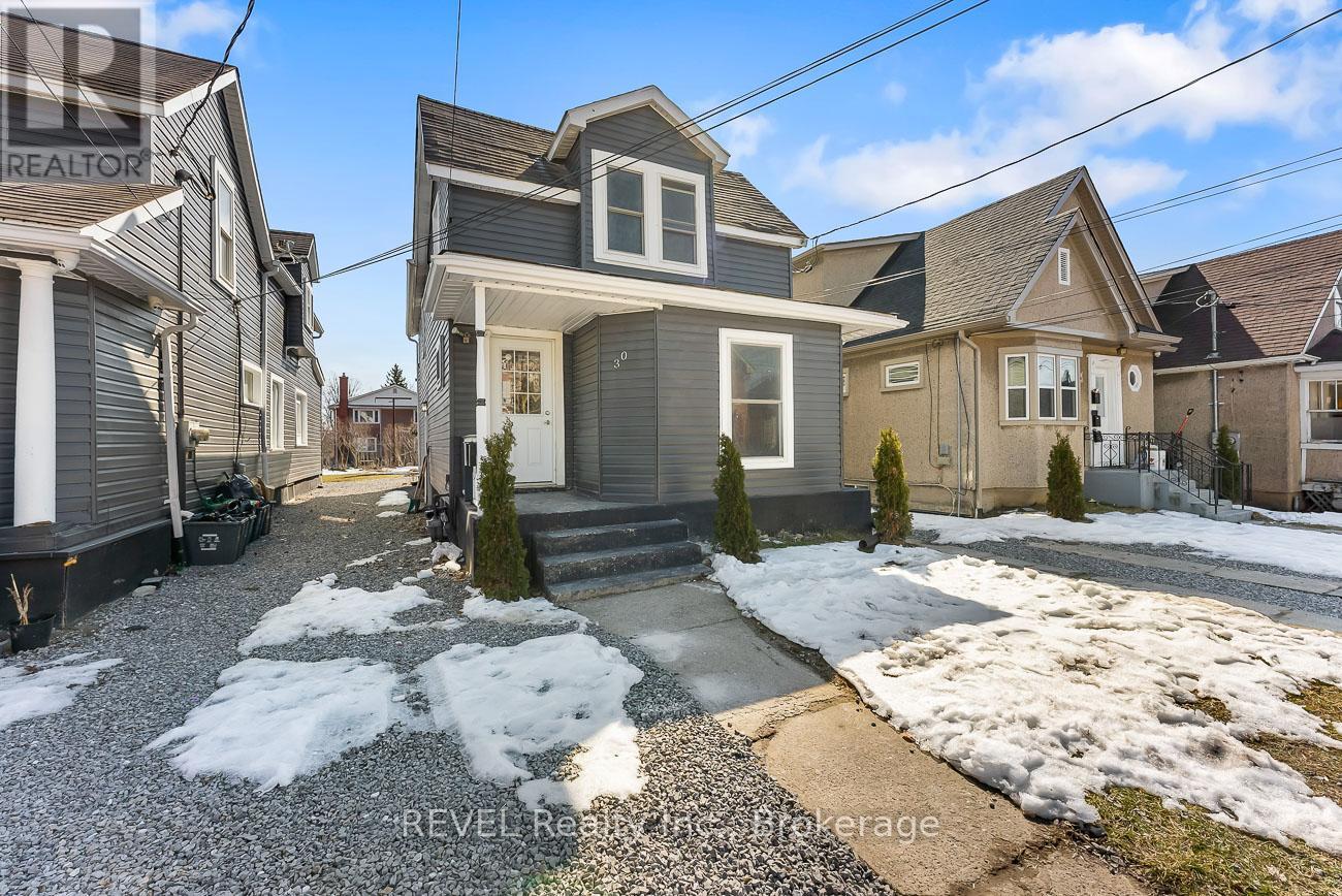 A house with a grey front yard and a small tree in front of it.