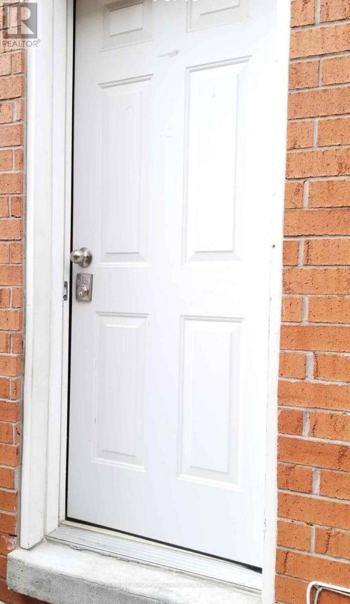 A white door with a silver handle is set in a brick wall.