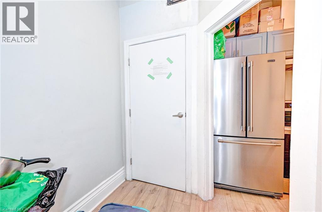 A white door with a green arrow on it is in a room with a fridge in the background.