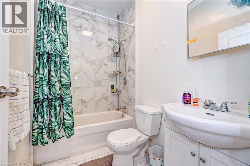 A bathroom with a white toilet, a white sink, and a shower with a green and white shower curtain.