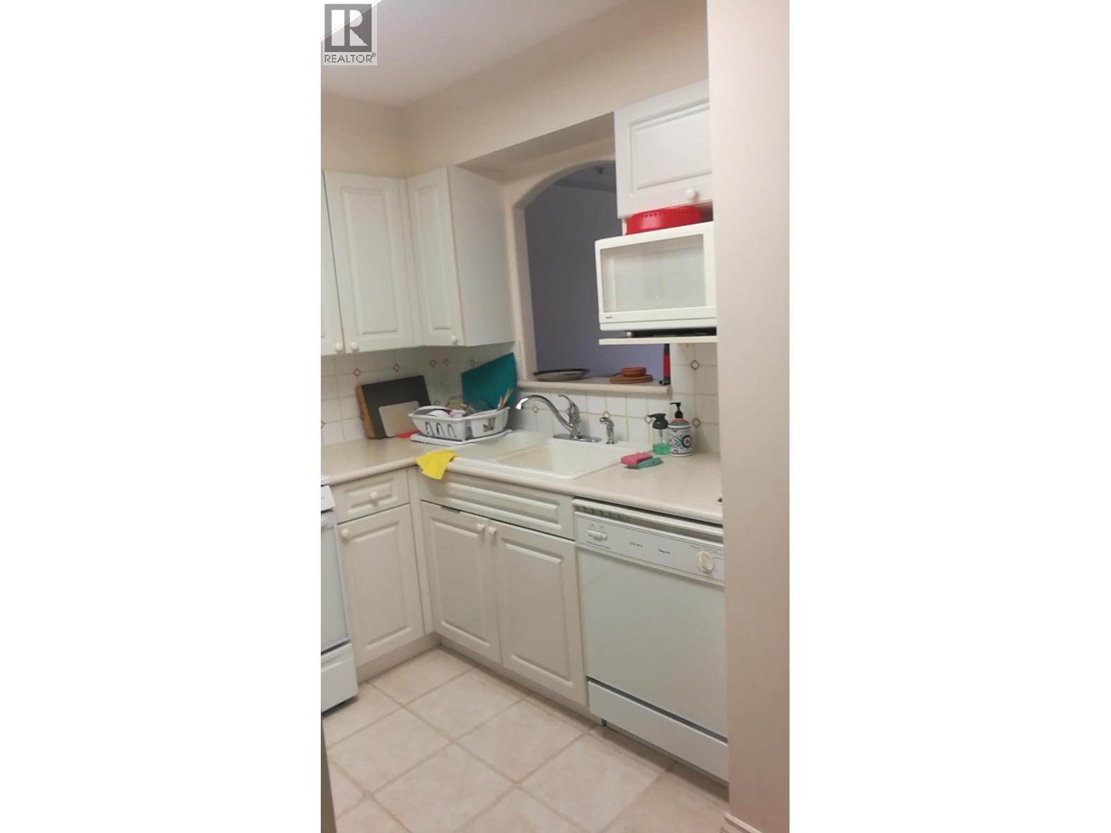 A kitchen with white cabinets and appliances.