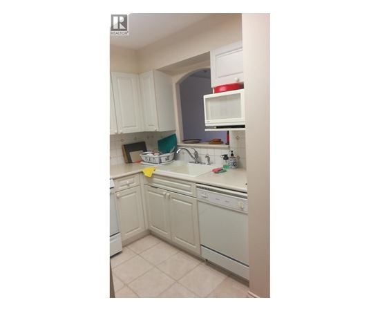 A kitchen with white cabinets and appliances.