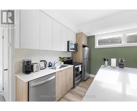 A kitchen with white cabinets and a green wall.