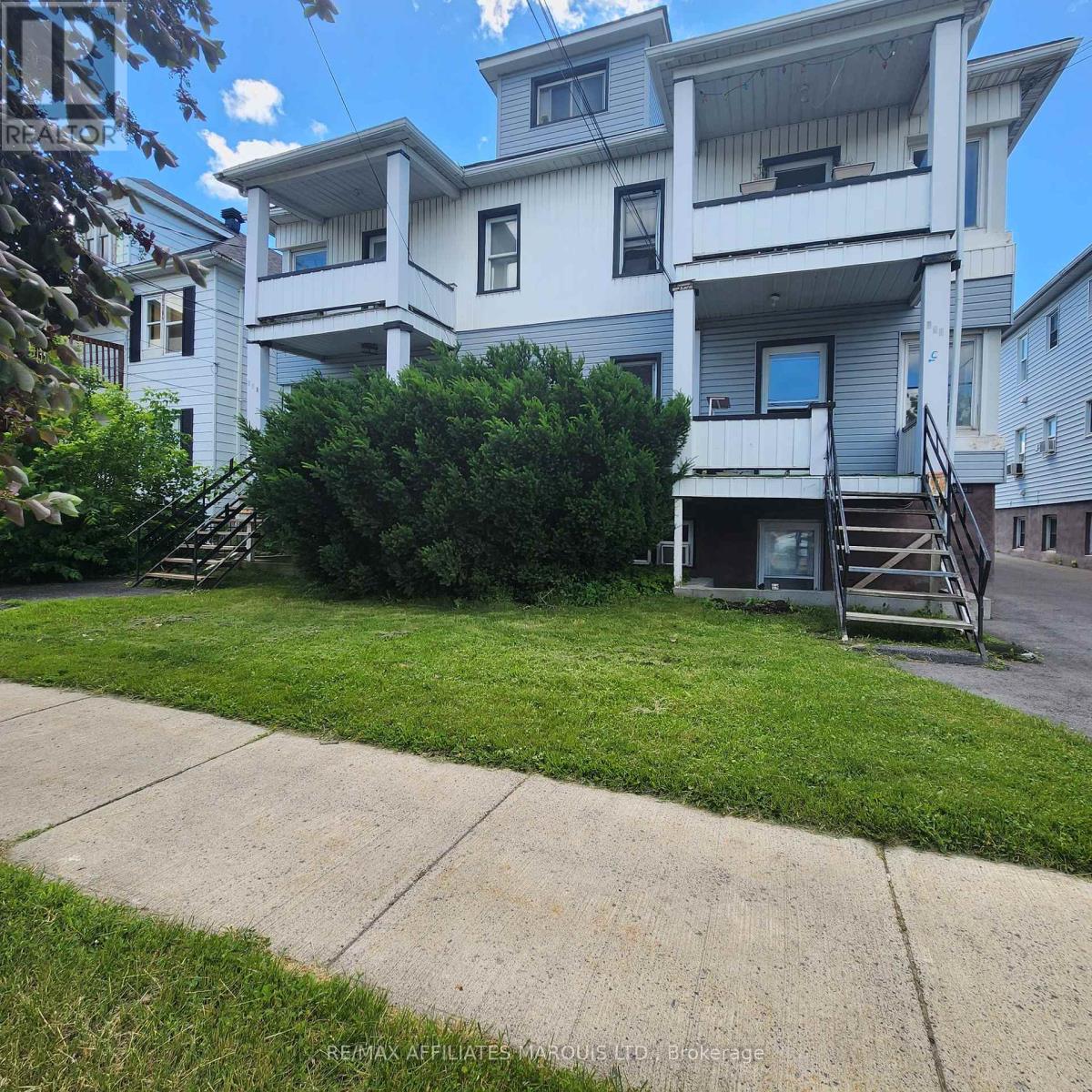 A large white apartment building with a green lawn in front.