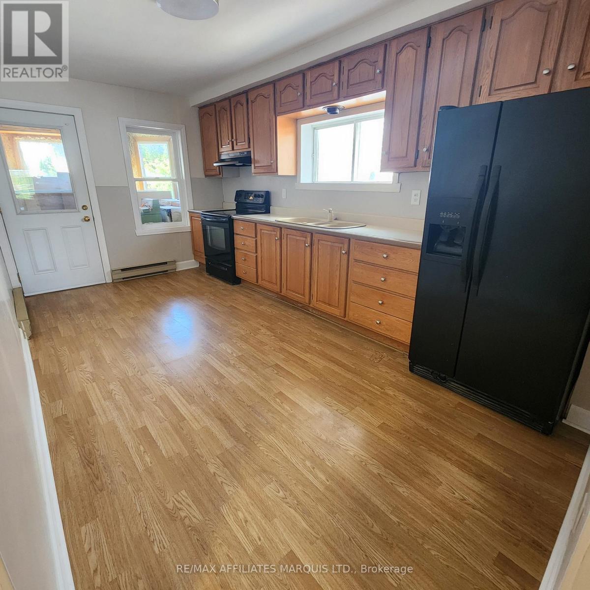 A kitchen with wooden floors and black appliances.