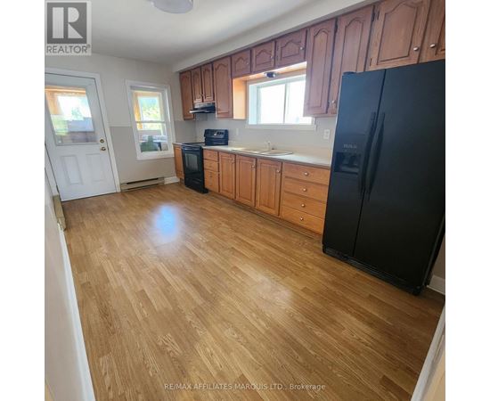 A kitchen with wooden floors and black appliances.