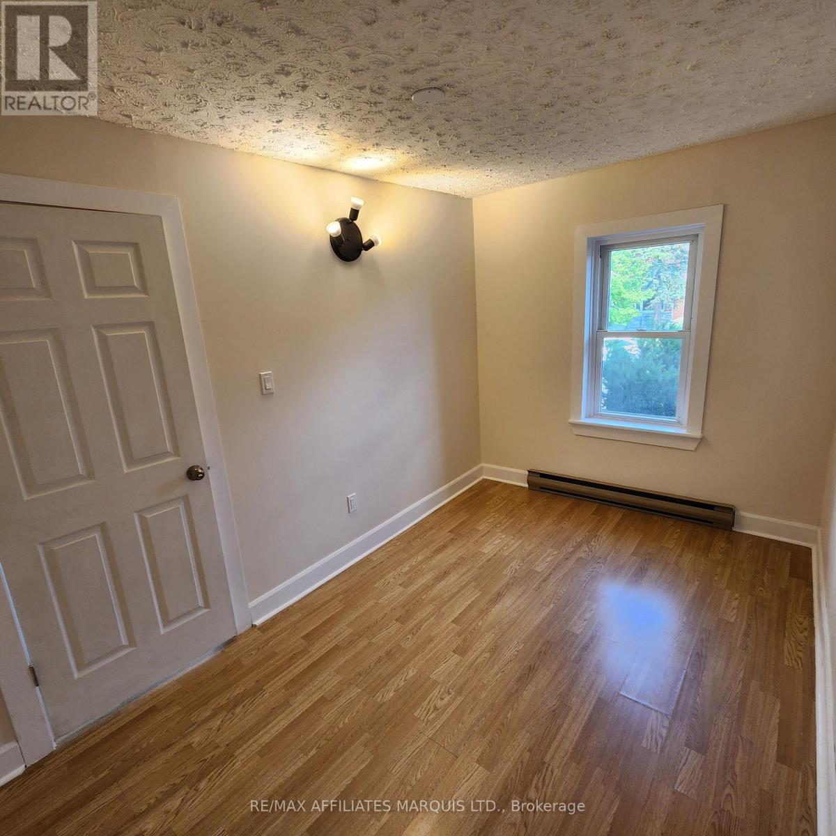 A room with a wooden floor and a window with a white frame.