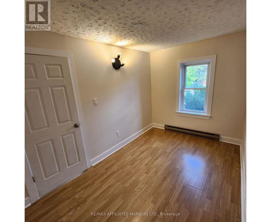A room with a wooden floor and a window with a white frame.