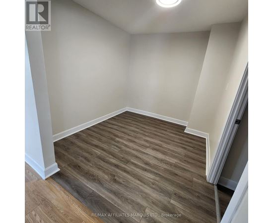 A room with wooden flooring and white walls.