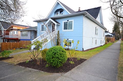 A blue house with a white fence and a small garden in front.