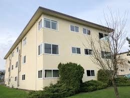 A beige building with a green lawn in front.
