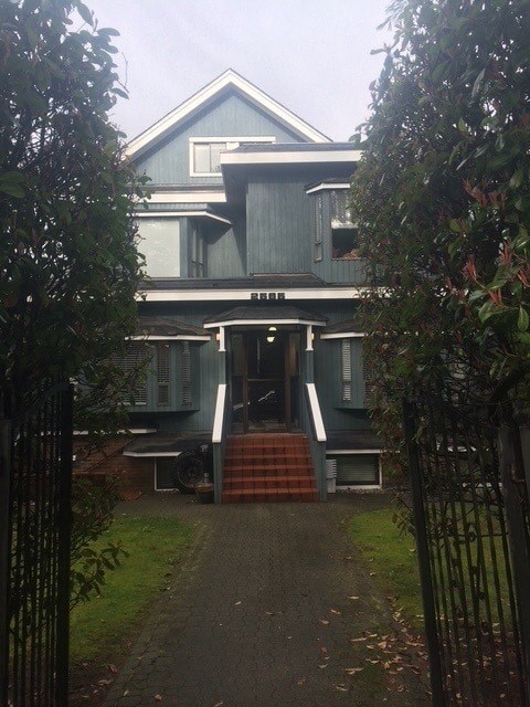 A house with a grey facade and a black gate.