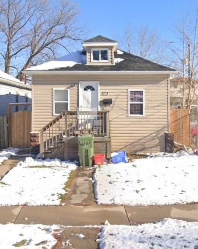 A small house with a snow-covered front yard.