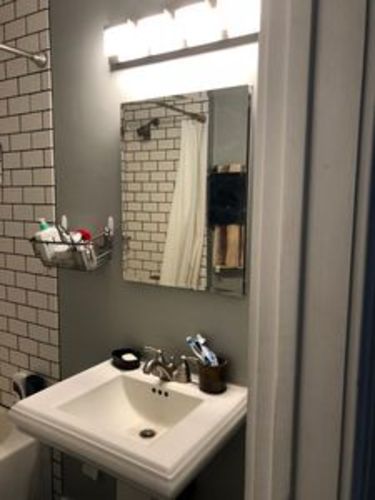 A white sink in a bathroom with a mirror above it.