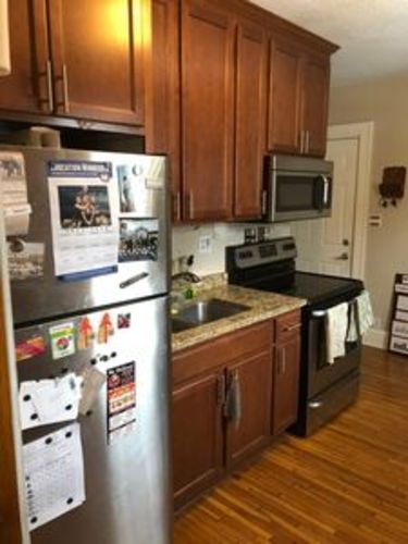 A kitchen with a refrigerator, microwave, and oven.
