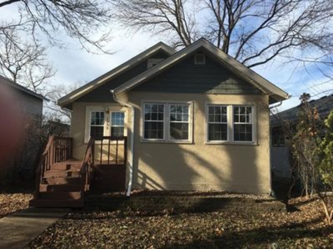A small house with a brown porch and a brown roof.