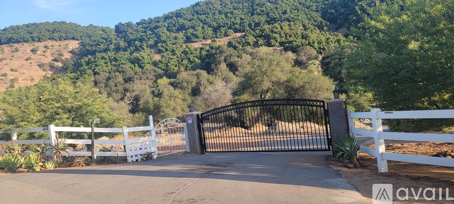 A black gate with a white fence on either side.