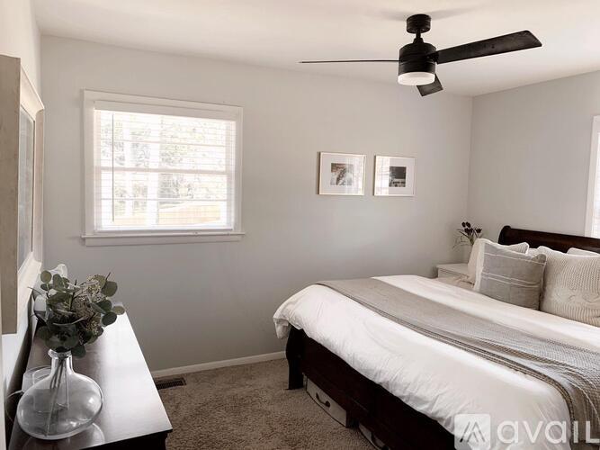 A bedroom with a bed, a ceiling fan, and a window.
