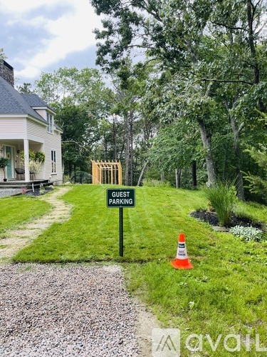 A sign that says "Guest Parking" stands in a grassy area.