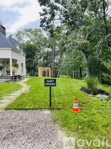 A sign that says "Guest Parking" stands in a grassy area.