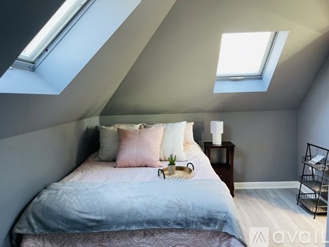 A bedroom with a bed, nightstand, and a window.