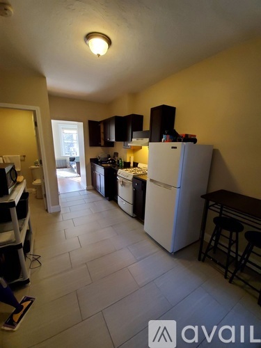 A kitchen with a white refrigerator and black cabinets.