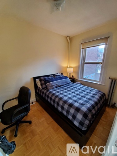A bedroom with a bed, chair, and window.