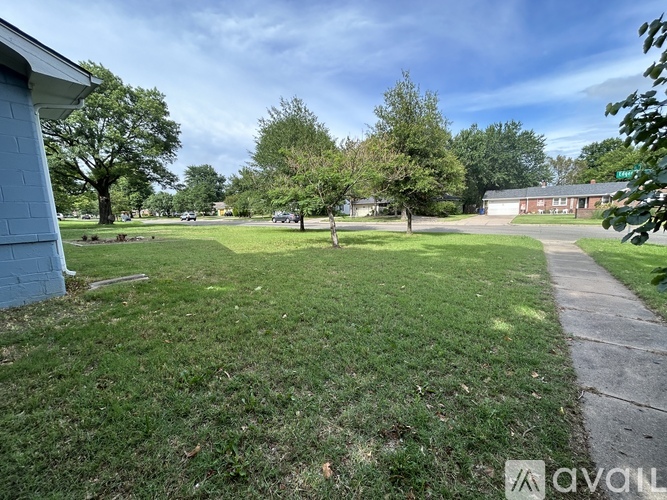 A grassy area with a sidewalk and a building in the background.