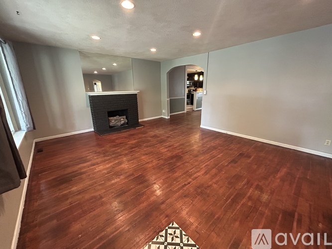 A spacious room with a fireplace and wooden flooring.
