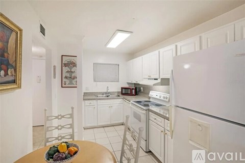 A kitchen with white appliances and a table with fruit on it.